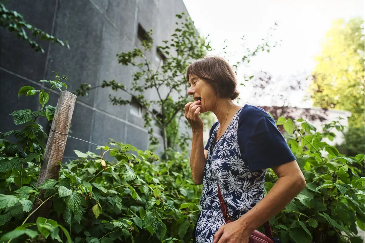Une femme goûte une baie dans un jardin urbain