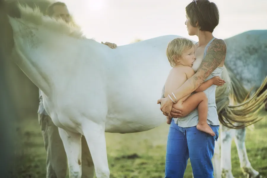 Une mère et son enfant près d’un cheval blanc