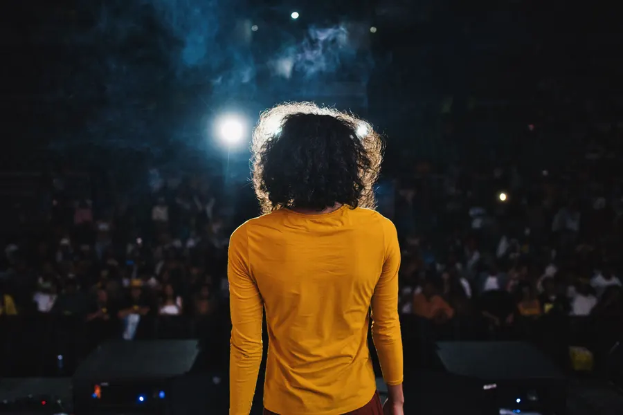 Une artiste de dos face au public, sous les projecteurs